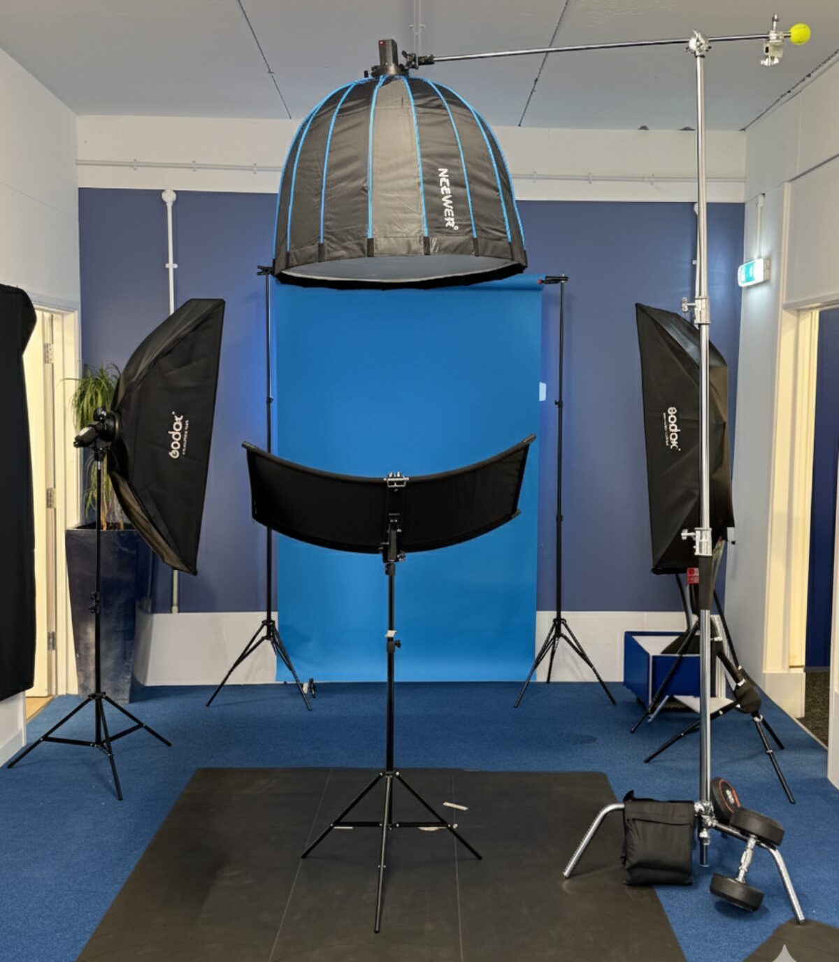 Professional headshot studio with blue backdrop, beauty dish, and two softbox lights
