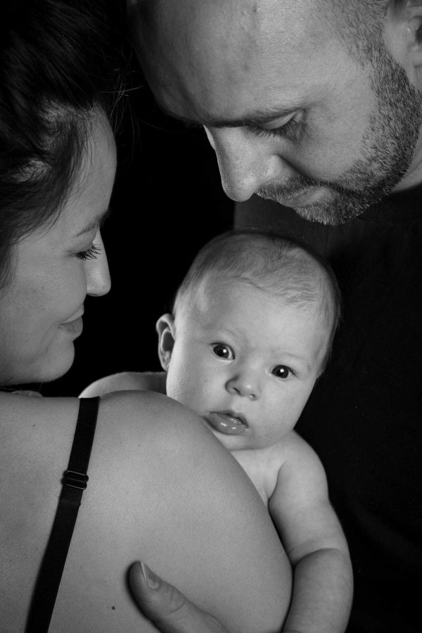 Baby, mother, and father studio shot, black and white.