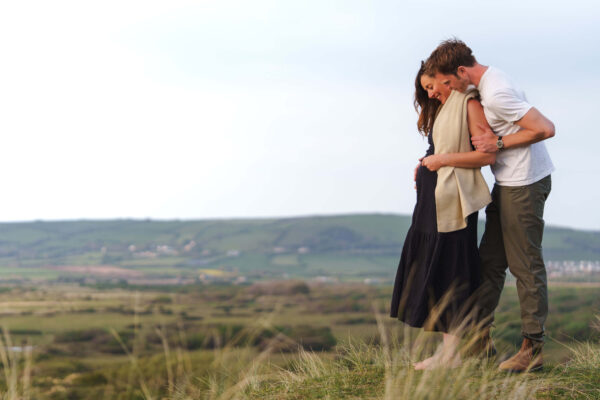 Family portrait of Fi and Freddy on a beach, sharing an intimate, natural moment in soft light.