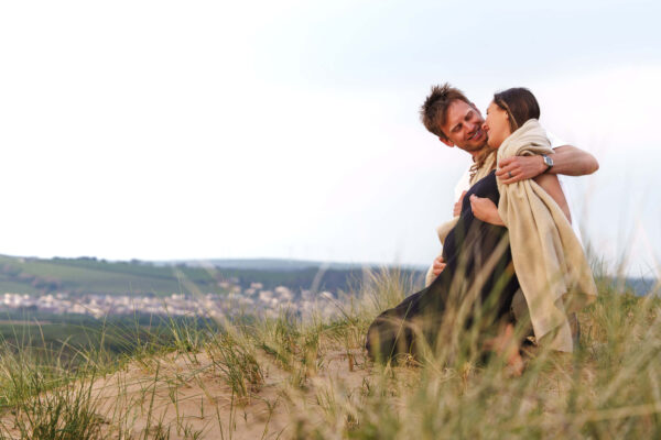 Family portrait of Fi and Freddy on a beach, sharing an intimate, natural moment in soft light.