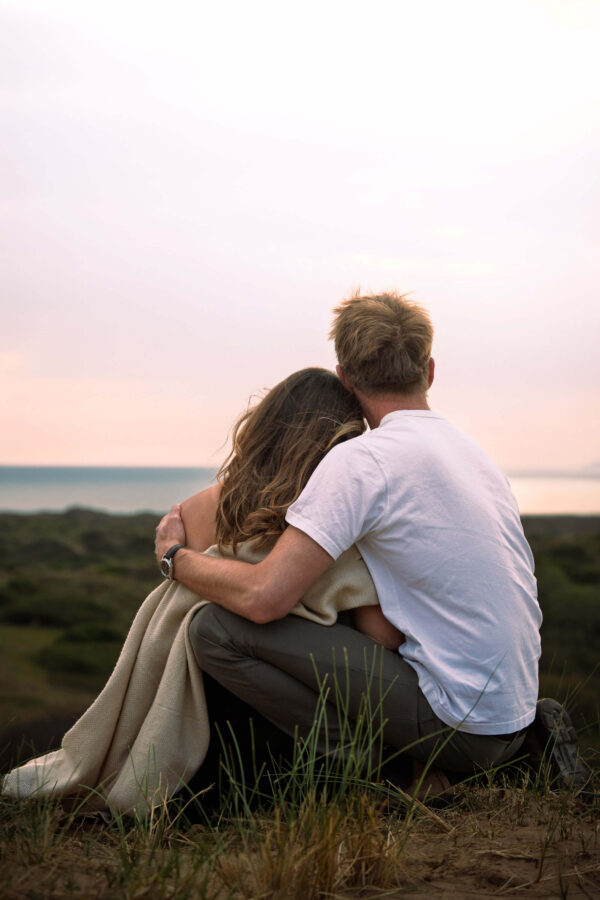 Family portrait of Fi and Freddy on a beach, sharing an intimate, natural moment in soft light.