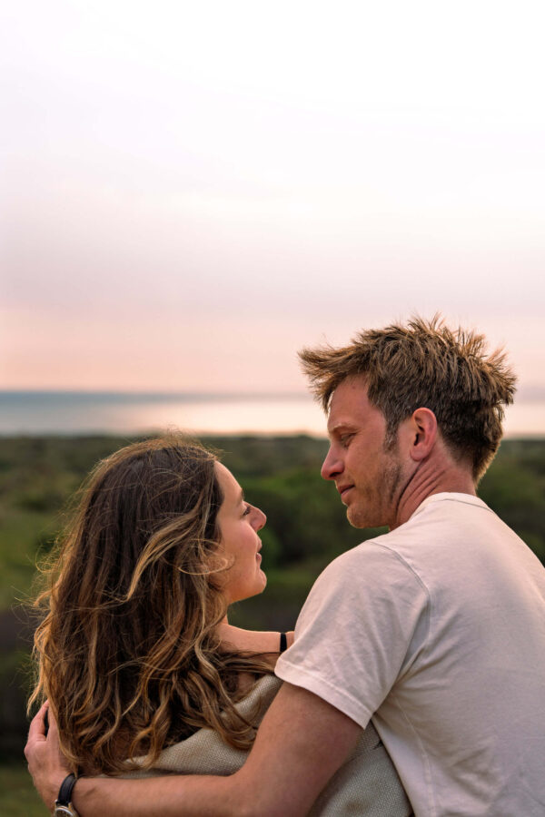 Family portrait of Fi and Freddy on a beach, sharing an intimate, natural moment in soft light.