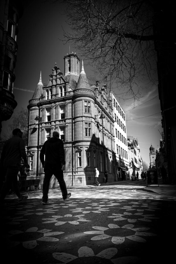 Person silhouetted against a Victorian Gothic building in Bristol city centre, strong directional light