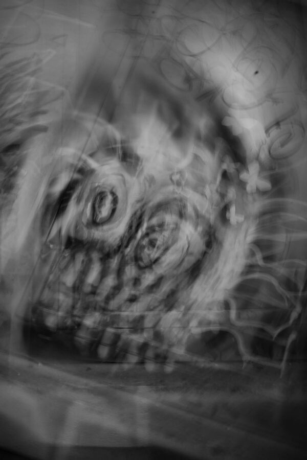 Motion-blurred street art mural on an urban wall, abstract and dreamlike, high contrast monochrome