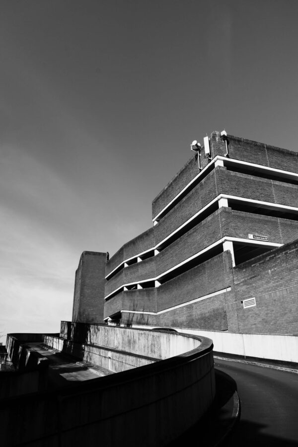 Brutalist multi-storey car park photographed from low angle, strong geometric lines in black and white
