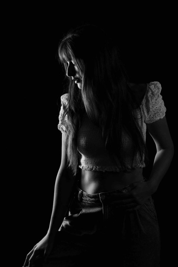 Black-white portrait, soft light, black background, woman posing to the right.