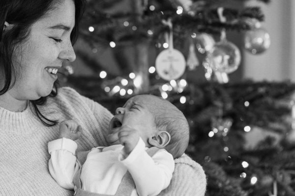 Mother with baby at Christmas in front of the tree.
