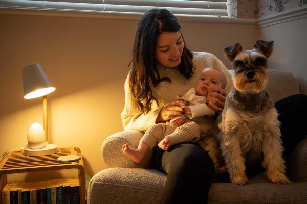 Baby, dog, and mother on seat in nursery.