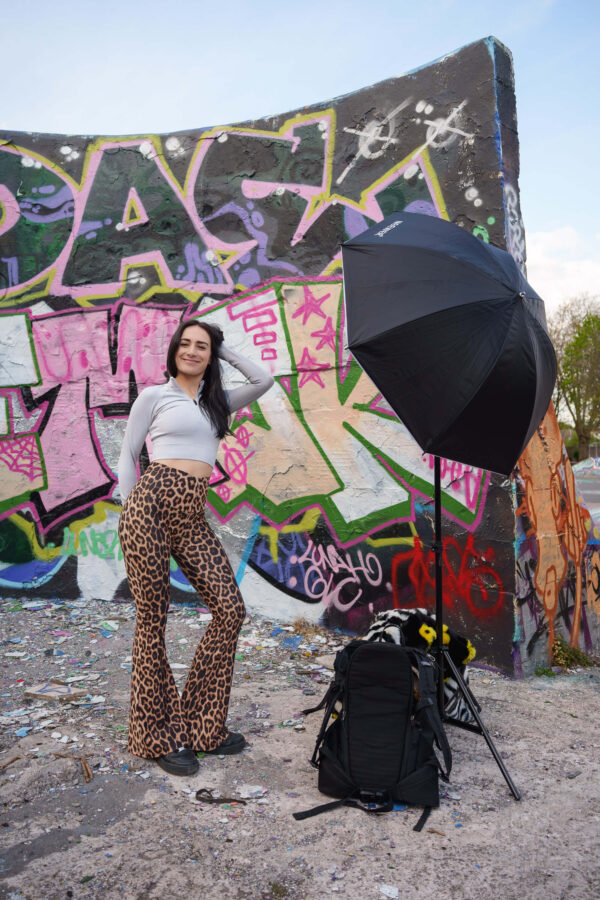 Portrait of a model in an urban street setting with graffiti background, showing camera gear